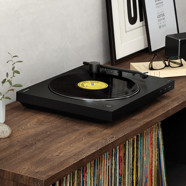 Record turntable on shelf full of vinyl records.